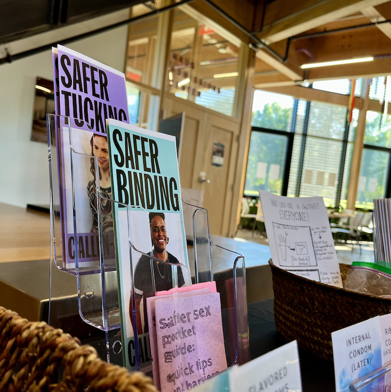 Pamphlets about "Safer Tucking" and "Safer Binding" sit on a table along with other materials.